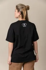 Remera gris con estampa de la letra M en negro y cadena plateada en el cuello.