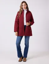 Campera capitoneada de largo midi en color bordó, con diseño de rombos en el cuerpo y mangas, y costuras diagonales en los laterales. Cuenta con cierre frontal, capucha desmontable con interior suave y panel entallado en la cintura.