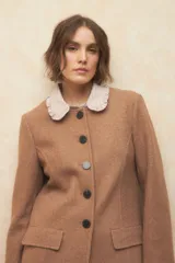 Tapado largo color crema, de paño, con cuello a la base y botones redondos veteados.