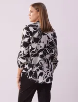 Blusa de gasa estampada con flores rojas y blancas, marca Floral & Ivy. Tiene cuello a la base con escote en V y mangas tres cuartos regulables con presilla y botón.