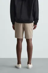 Bermuda negra de corte recto, con cintura elástica ajustable mediante cordón, pliegues frontales y bolsillos de vivo en la espalda. El bajo tiene un dobladillo vuelto.