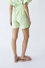 Short verde de lino con bolsillos delanteros, cintura elastizada y cordón ajustable en blanco y negro.