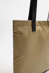 Bolso tipo shopper color beige, fabricado en tejido técnico con asas de mano de piel color negro. Tiene compartimento principal con cierre de imán y bolsillo interior con cremallera.