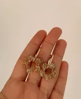 Aros tipo argolla con dije colgante en forma de flor realizado en acrílico con acabado brillante y destellos iridiscentes.