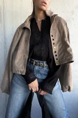 Camisa negra de corte holgado con detalles de encaje floral en la parte frontal y en los puños, cierre frontal con botones y cuello clásico.