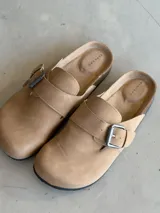 Zuecos color beige con hebilla metálica ajustable, plantilla anatómica y suela de corcho.