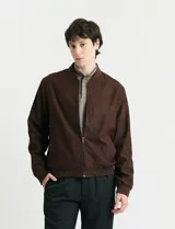Campera tipo bomber de color marrón, confeccionada en tejido con textura similar a la gamuza, con cierre frontal completo, cuello redondo y puños elásticos.
