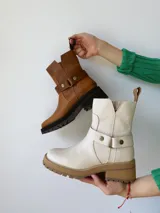Botas cortas color crudo de cuero, con cierre lateral, pulsera desmontable y suela marrón.