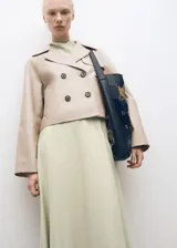 Abrigo corto tipo chaqueta de cuero ovino color beige, con diseño de doble botonadura, solapas con muesca y manga larga.