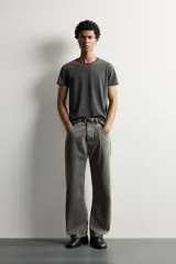Jeans loose fit de hombre en denim de algodón color gris oscuro con efecto lavado. Presenta perneras con costuras giradas hacia los tobillos, tiro medio, cierre frontal con botones y bolsillos frontales con bolsillo cerillero.