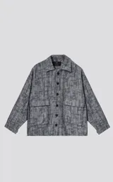 Campera de denim rígido con diseño de trama texturizada en tonos grises y negros. Presenta cuello camisero, cierre frontal con botones, mangas largas y dos bolsillos frontales con solapa.