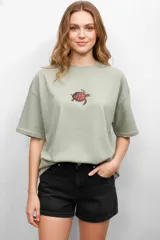 Remera de algodón color verde oliva, de corte holgado y manga corta, con cuello redondo y estampado central de una tortuga marina.