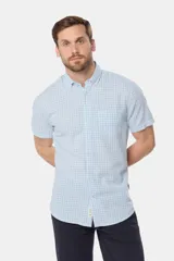 Camisa de lino de manga corta con estampado a cuadros en tonos celestes y blancos, cuello con botones y bolsillo ojal en el pecho.