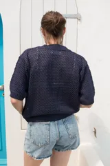 Saco tejido de punto calado con mangas al codo, cuello redondo y cierre frontal con botones de coco. Presenta un diseño versátil y ligero.
