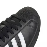 Championes Adidas Superstar de cuero negro con las icónicas tres tiras laterales en blanco, puntera de goma clásica y logo en la lengüeta y el talón.
