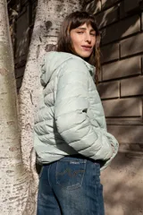 Campera puffer ultraliviana color beige, con diseño acolchado horizontal, capucha incorporada, cierre frontal y bolsillos laterales.