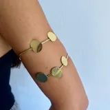Brazalete dorado para el brazo con círculos decorativos.