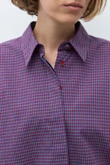 Camisa de manga larga con estampado de cuadros pequeños en tonos violeta y rojo, con cuello clásico y cierre frontal de botones.