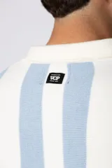 Chomba de punto con diseño de rayas verticales en color celeste y blanco, cuello tipo polo con cierre de botones y mangas cortas.