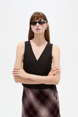 Musculosa de algodón sin mangas, de corte cruzado con cuello en V y diseño holgado, color blanco con estampado de lunares bordó y lazo lateral para ajustar.