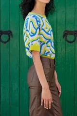 Remera de tejido de punto con estampa abstracta en colores blanco, azul y verde. De calce recto, con cuello redondo y manga corta.