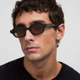 Lentes de sol con armazón de acetato negro y forma ovalada angular. Poseen cristales polarizados en tono marrón con protección UV400.