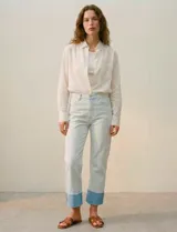 Jean de algodón de tiro medio, color celeste muy claro, con un dobladillo ancho y contrastante en color azul claro en los tobillos. El corte es recto o ligeramente holgado.