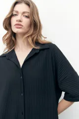 Vestido camisero negro con textura plisada, corte midi y cierre frontal con botones.