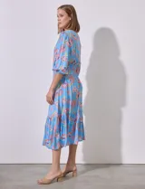 Vestido midi celeste con estampado floral en tonos naranja y rosa, de la marca Ruby Rd. Tiene cuello redondo con escote en V, mangas 3/4 con puños fruncidos y cintura elastizada en punto smock.