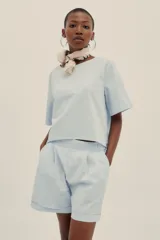 Conjunto celeste a rayas verticales, compuesto por un top corto de mangas cortas y un short de tiro alto con pinzas.