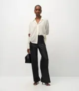 Pantalón wide leg de poliuretano color negro, con cintura de tiro alto, trabillas para cinturón, cierre frontal y bolsillos traseros aplicados.