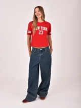 Remera negra de manga corta con estampado frontal que dice "WEST COAST California" en blanco y detalles gráficos en las mangas.