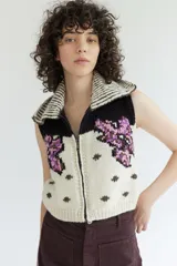 Chaleco de tejido de punto con cierre frontal, cuello solapa y diseño estampado con motivos florales en tonos violeta, negro y crudo.