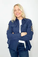 Sobre camisa azul marino de algodón con cierre de botones, dos bolsillos frontales con solapa y detalle de galones en color beige en las mangas.