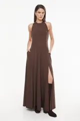 Vestido largo azul marino, de corte fluido, con escote halter, detalles trenzados en los hombros, bolsillos laterales y tajo profundo en la pierna.