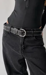 Cinto de cuero sintético negro con diseño de doble hilera de tachas metálicas plateadas y hebilla metálica clásica.