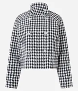 Saco corto estructurado con estampado pied de poule en blanco y negro. Presenta cuello alto, cierre frontal cruzado con botones decorativos y mangas largas.