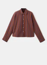 Blusa de algodón marrón con rayas verticales azules, corte recto, cuello camisero, manga larga con puños abotonados y cierre frontal de botones.