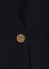 Cardigan de punto azul marino, con diseño cruzado, escote en V y cierre de un botón dorado en el lateral. Mangas largas abullonadas en los hombros.