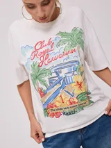 Remera blanca de algodón con estampa frontal de estilo retro con palmeras, flores y texto "Club Royal Hawaiian" y "The Whole World Knows Waikiki".