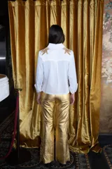 Pantalón dorado de corte acampanado con aberturas laterales en el ruedo.