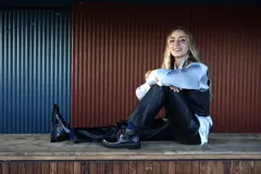 Borcegos de cuero charolado negro con cordones jaspeados en tonos marrones y suela track dentada con costura blanca visible.