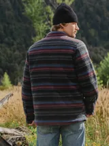 Camisa overshirt de micropolar con diseño a rayas horizontales multicolor. Cuenta con cuello clásico, cierre frontal de botones, dos bolsillos superiores con solapa y bolsillos laterales. El interior está forrado con tafeta acolchada para mayor abrigo.