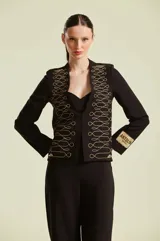 Saco sastrero negro de mujer con intrincados bordados dorados estilo militar en los paneles frontales y detalle de etiqueta de la marca en la manga.