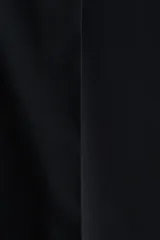 Pantalón ancho negro de corte holgado con pinzas, cierre frontal oculto y pliegues marcados en las piernas.
