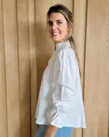 Blusa de algodón con cuello mao y volados, mangas largas con puños elásticos y corte holgado.