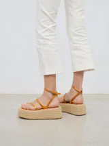 Sandalia con plataforma de esparto, tiras color cobre y cierre con hebilla al tobillo.