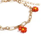 Pulsera dorada con eslabones grandes y pequeños, con dijes de flores rojas con centro amarillo.
