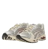 Championes Asics Gel-Kayano 14, en color beige y plateado con detalles en bordó, confeccionados con malla transpirable y superposiciones sintéticas, con suela amortiguada para mayor confort.