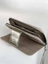 Billetera grande de cuero en color natural, con solapa externa en cuero metalizado dorado que presenta un logo grabado de un búho. El interior cuenta con múltiples ranuras para tarjetas y el nombre de la marca grabado.